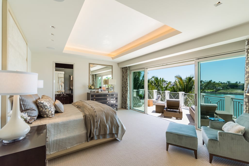 second story bedroom with open sliding glass doors looking out at the canal