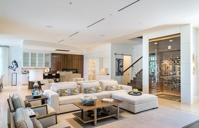 living room with white couch, coffee table, kitchen in the background, and stairs leading upstairs