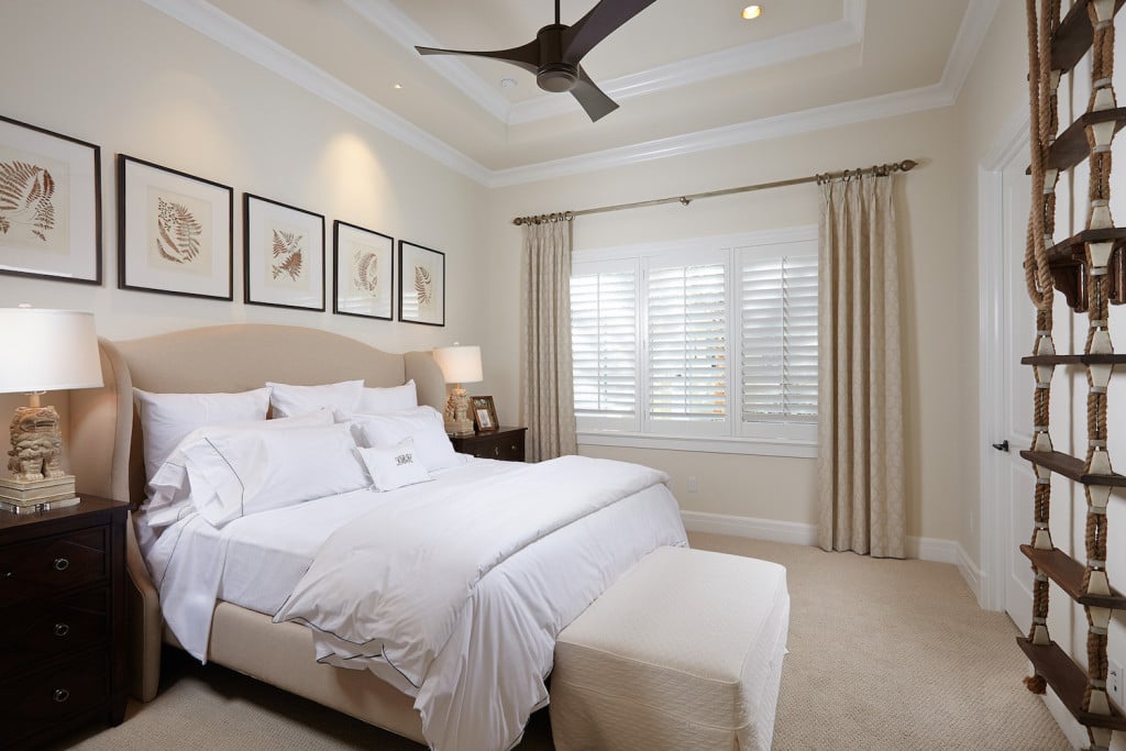 bedroom with a bed with white pillows and sheets, tan bed frame and curtains