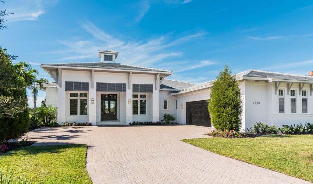 exterior of Florida home with red paver driveway and white exterior