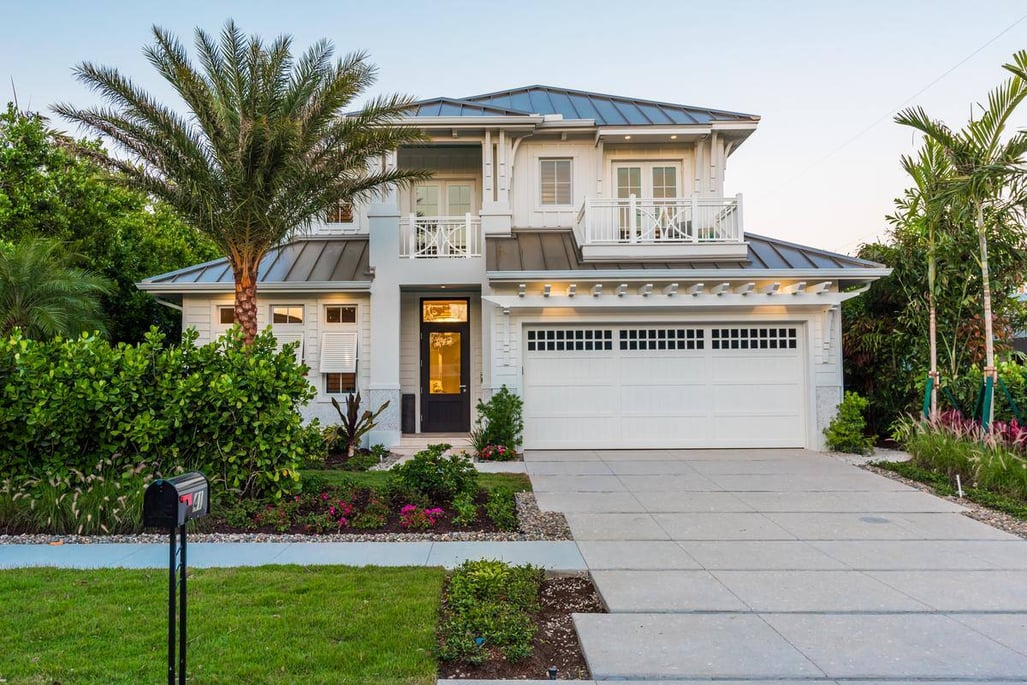 two story white exterior home with its outdoor lights on and a palm tree in the front yard