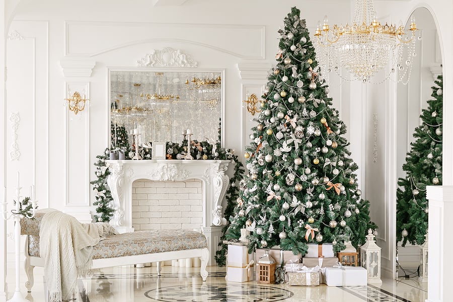 a decorated Christmas tree next to a fireplace in a white living room